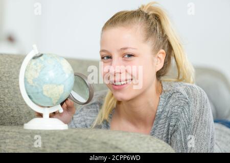 woman holding magnifying glass over globe Stock Photo