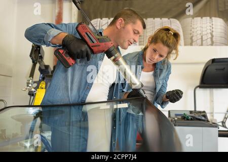 glazier using tools repairing fix crack broken windshield Stock Photo
