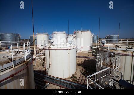White oil storage tanks of oil refinery plant in desert under bright sun on deep blue sky. Oil and gas processing plant near Taraz city, Kazakhstan. Stock Photo