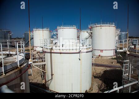 White oil storage tanks on oil refinery plant in desert. Under bright sun on deep blue sky. Oil processing plant near Taraz city, Kazakhstan. Stock Photo