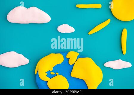 The planet Earth and Sun with clouds in the sky. Scene is made out of polymer clay. Stock Photo
