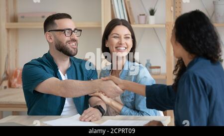 Happy young couple making deal, smiling husband shaking manager hand Stock Photo