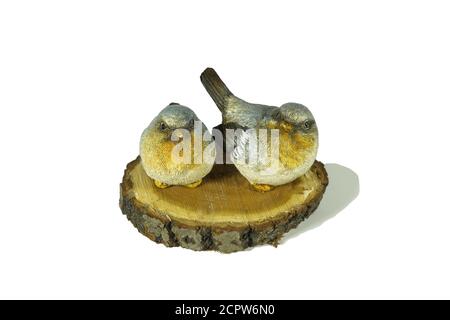 Two ceramic small grey and yellow birds sit on a natural birch saw cut isolated on white background. Interior decorations. Stock Photo