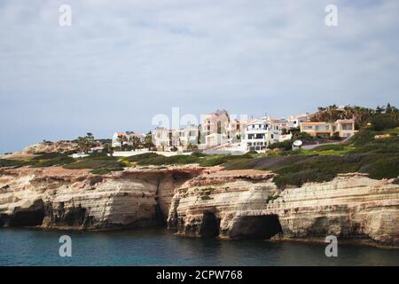 Cyprus, Mediterranean sea, Sea Caves, Rocky Coast with a city above Stock Photo