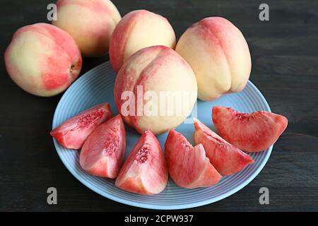 Plate of Cut Fresh Ripe Peaches for Dessert with Whole Fruits in Background Stock Photo