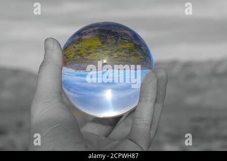 Reflection of desert landscape in glass ball, only the orb is in color the rest is black and white. Stock Photo