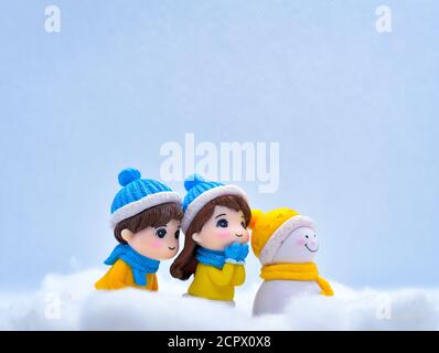 Tourism and travel concept: Miniature people looking for something in winter snow along with little snowman Stock Photo