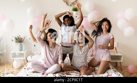Energetic young diverse multiethnic girls playing with colorful confetti. Stock Photo