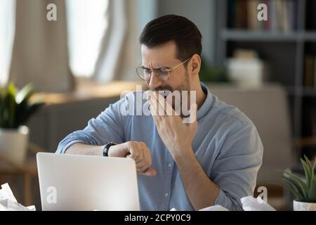Tired young male worker sigh wait for work finish Stock Photo