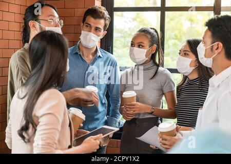 Group of business worker team meeting and brainstorm for startup new business. They wear protective face mask in new normal office preventing coronavi Stock Photo