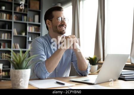 Smiling man distracted form laptop dreaming of success Stock Photo