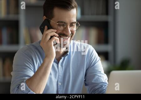 Smiling young man talking on phone with client Stock Photo