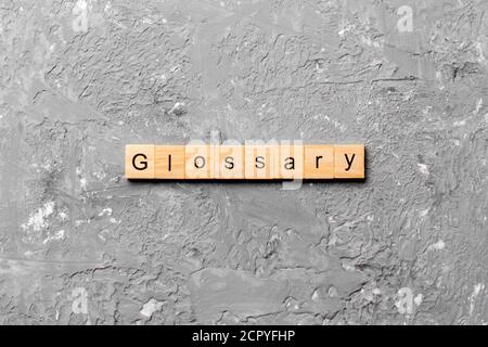 Glossary word written on wood block. Glossary text on cement table for your desing, Top view concept. Stock Photo