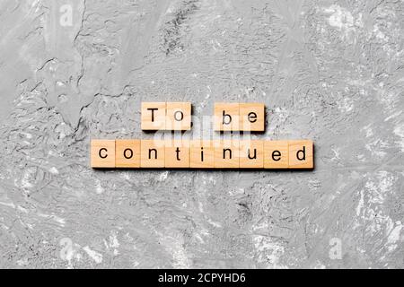 To be continued word written on wood block. To be continued text on cement table for your desing, concept. Stock Photo