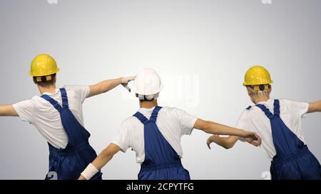Three male construction workers in hard hats synch dancing with Stock Photo