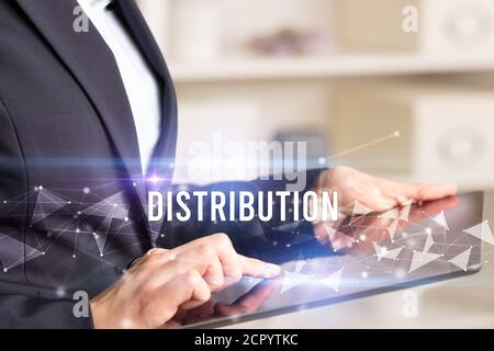 Close up hands using tablet with DISTRIBUTION inscription, modern business technology concept