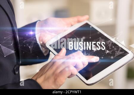 Close up hands using tablet with BUSINESS inscription, modern business technology concept