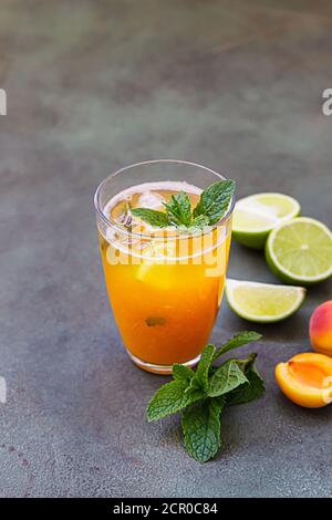 Glass with refreshment mocktail with apricot, mint and lime on green background. Cold cocktail or iced tea. Stock Photo