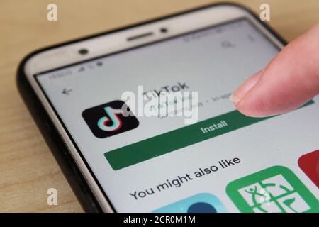 A finger pressing the install button on the google play store, downloading the app Tiktok on a phone Stock Photo