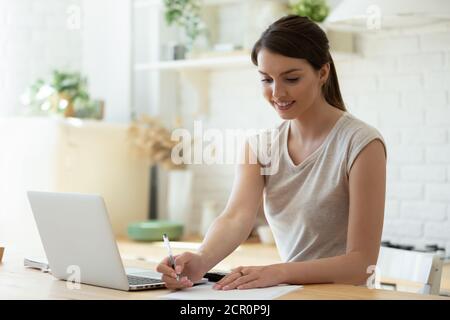 Young lady doing paperwork using laptop and calculator Stock Photo