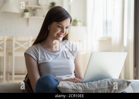Cheerful young lady using laptop at home Stock Photo
