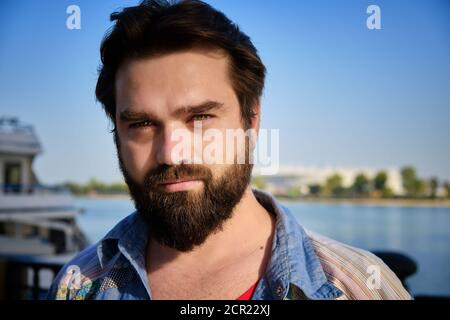 Portrait of bearded caucasian man with river and blue sky at background Stock Photo