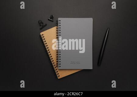 A top view of notebooks and a pen on a black surface Stock Photo