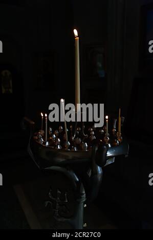 Candle stick with some burning candles in the dark empty room Stock Photo