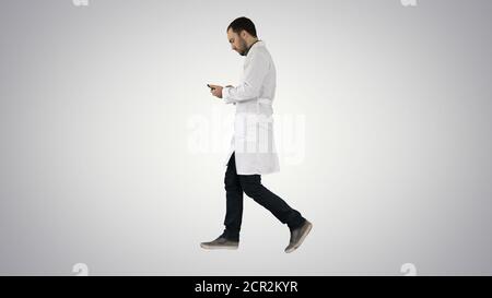Male doctor walking and using mobile phone on gradient backgroun Stock Photo