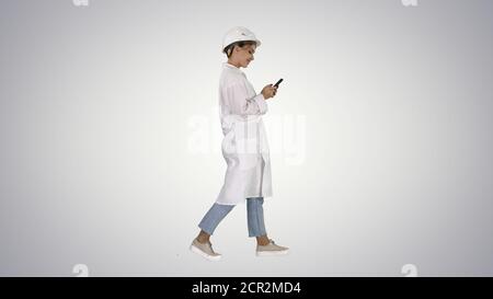 Female Scientist Using Smartphone Walking on gradient background Stock Photo