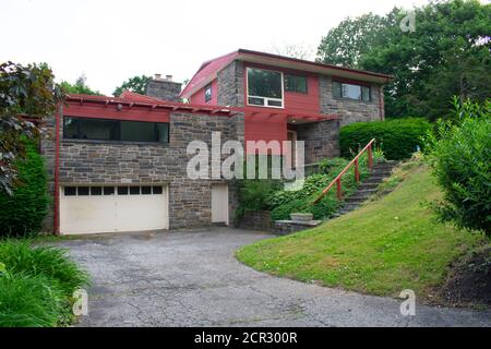 A Modern Cobblestone House With a Red Trim and a Red Roof and Driveway Stock Photo
