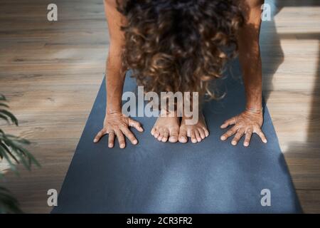 Standing Forward Bend pose in yoga iyengar, Uttanasana fold pose close up front view in studio Stock Photo