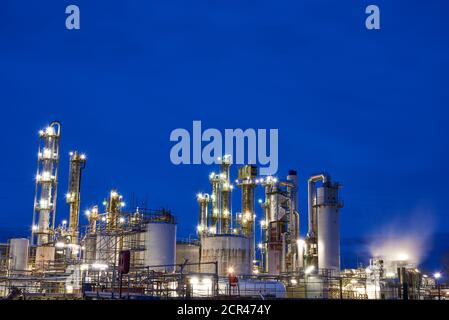 Oil refinery with a cooling tower with free cooling after sunset with lights Stock Photo