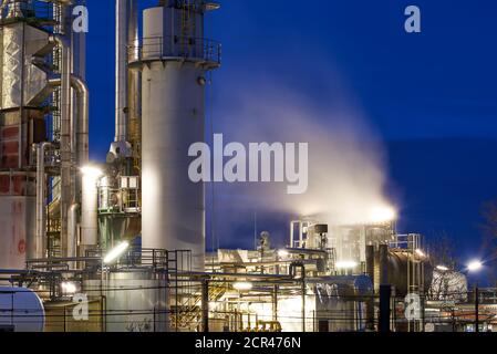 Petroleum refinery with a cooling tower and fog from free cooling after sunset with lights Stock Photo