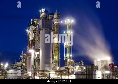 Petroleum refinery with a cooling tower with free cooling after sunset with lights Stock Photo