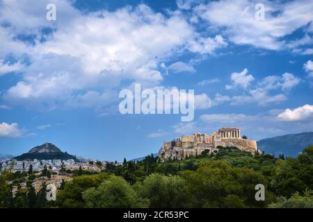 Iconic view of Acropolis hill and Lycabettus hill in background in Athens, Greece from Pnyx hill in summer daylight with great clouds in blue sky. Stock Photo