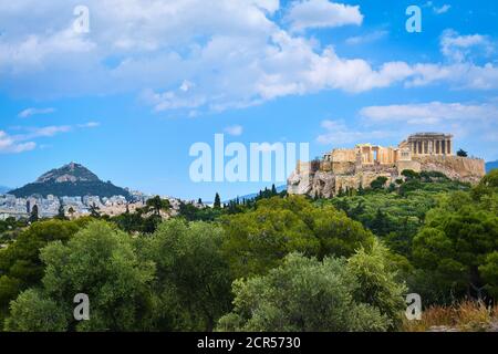 Iconic vew of Acropolis hill and Lycabettus hill in background in Athens, Greece from Pnyx hill in summer daylight with great clouds in blue sky. Stock Photo