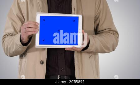Male hands holding tablet with blue screen mockup on gradient ba Stock Photo