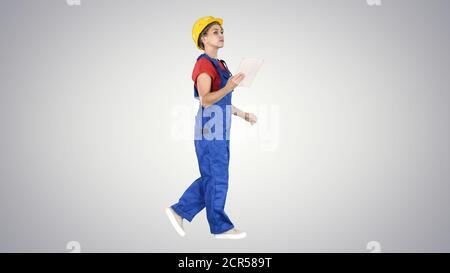 Construction lady using electronic tablet walking on gradient ba Stock Photo