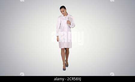 Woman doctor walking with tablet in hands on gradient background Stock Photo
