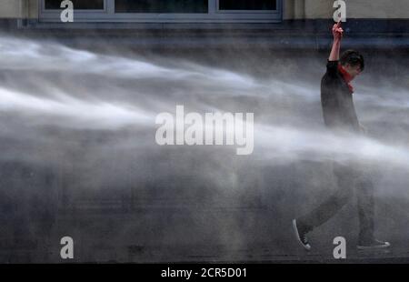 A demonstrator gestures in front of riot police as he is sprayed by water canons during a protest by European workers and trade union representatives to demand better job protection in the European Union countries in Brussels March 24, 2011. Tens of thousands of people marched through Brussels on Thursday to urge European leaders holding a two-day summit in the Belgian capital to scrap or ease austerity measures, which unions say will slow economic recovery and punish the poor. REUTERS/Eric Vidal (BELGIUM - Tags: POLITICS CIVIL UNREST BUSINESS IMAGES OF THE DAY)