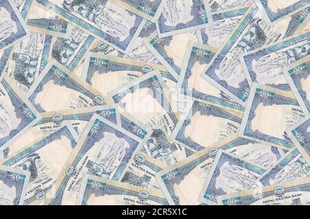 50 Nepalese rupees bills lies in big pile. Rich life conceptual background. Big amount of money Stock Photo