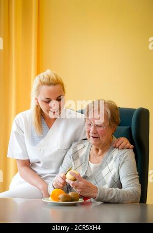Generations in dialogue. In the day clinic of a geriatric unit, a patient is cared for during everyday exercises by a young woman doing voluntary serv Stock Photo