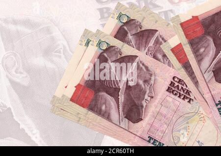 10 Egyptian pounds bills lies in stack on background of big semi-transparent banknote. Abstract presentation of national currency. Business concept Stock Photo