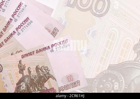 100 russian rubles bills lies in stack on background of big semi-transparent banknote. Abstract business background with copy space Stock Photo