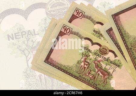 10 Nepalese rupees bills lies in stack on background of big semi-transparent banknote. Abstract presentation of national currency. Business concept Stock Photo