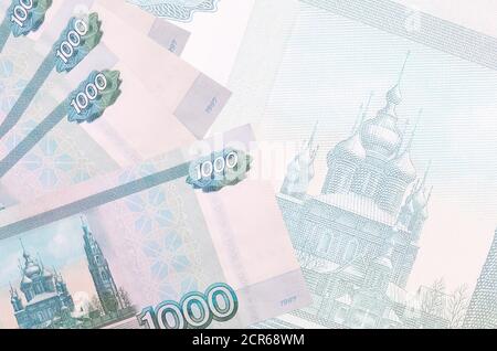 1000 russian rubles bills lies in stack on background of big semi-transparent banknote. Abstract business background with copy space Stock Photo