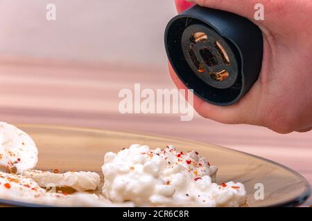 Putting red indian spice on white cottage cheese Stock Photo