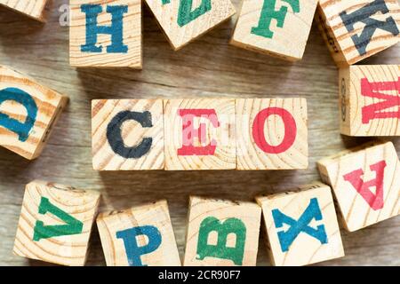 Alphabet letter block in word CEO (Abbreviation of Chief Executive Officer) with another on wood background Stock Photo