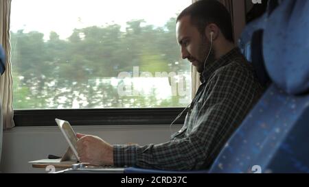 Serious man watching news on a tablet in a train. Stock Photo